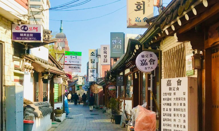 A narrow market street with Korean signs outside.