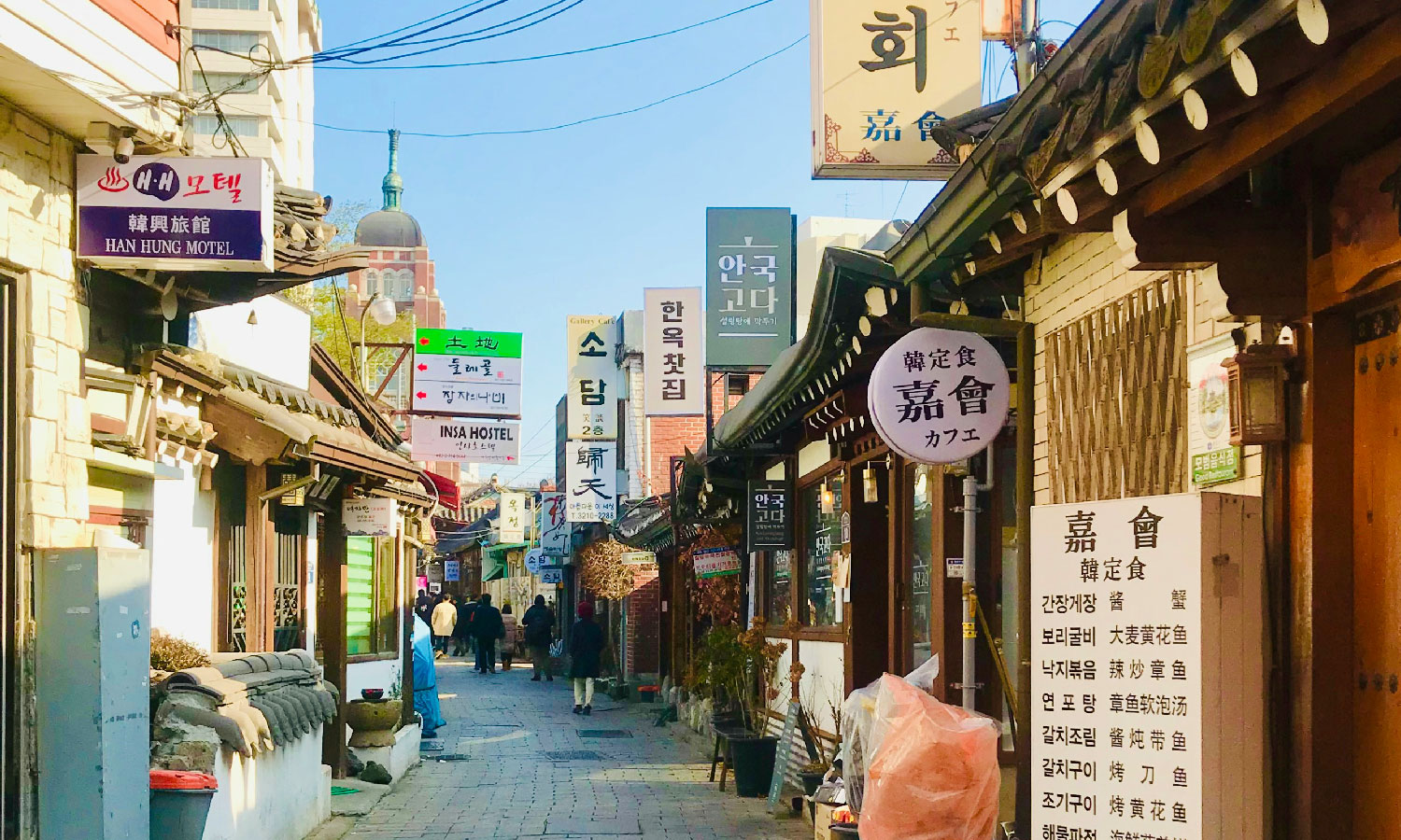 A narrow market street with Korean signs outside.